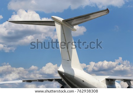 View from bottom on airplane tail with horizontal stabilizer against of a cloudy sky background  Royalty-Free Stock Photo #762938308