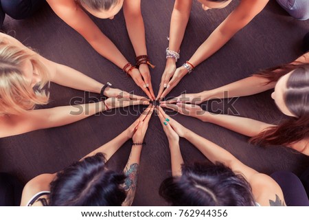 Close up hands of Group of sporty happy people sitting on the gym floor in a circle together, resting and meditating after yoga class with instructor indoors. Healthy lifestyle concept