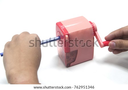 Male is sharpening the pencil with pink desktop pencil sharpener on a white background.