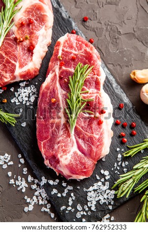 Raw fresh marbled meat. Steaks and rosemary on dark background
