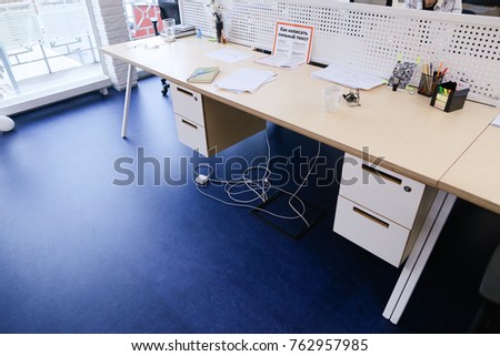 Simple computer light table for work, on which there are various devices and gadgets. Office space with blue floor. Concept of work area and computer room, education and prospects in work, arrangement