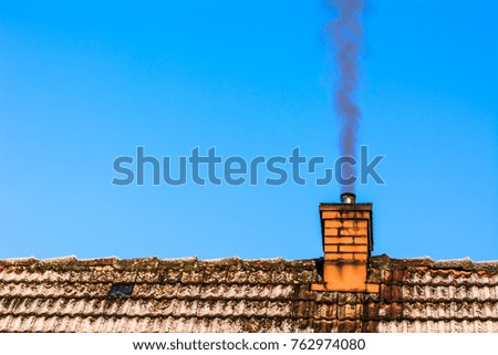 Old house roof with chimney smoke, air pollution and smog in winter, ecological problems