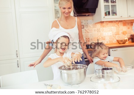 Cooking healthy food at home in the white kitchen. Happy family in the kitchen. Mother and children daughters are preparing the apple cake