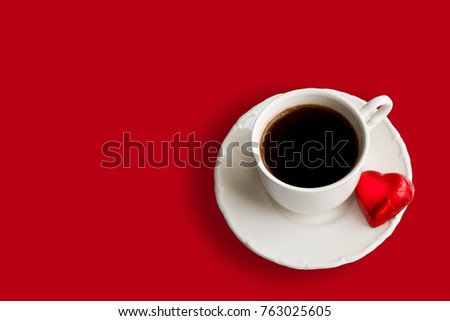 Cup of coffee with heart shaped candy isolated on red background with free space for your text