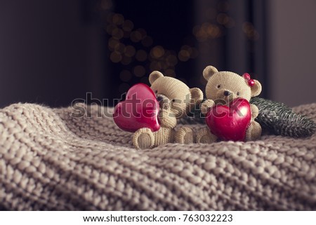 Two Little brown bear with red heart on woden table and blur background of New Year Tree. New year Theme. Christmas Time