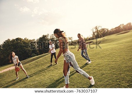 Summer activity. Group of young people in casual wear playing while spending carefree time outdoors