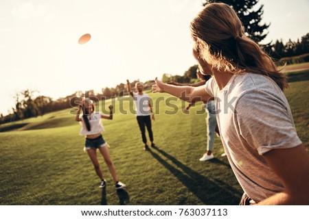You just have to catch! Group of young people in casual wear playing while spending carefree time outdoors