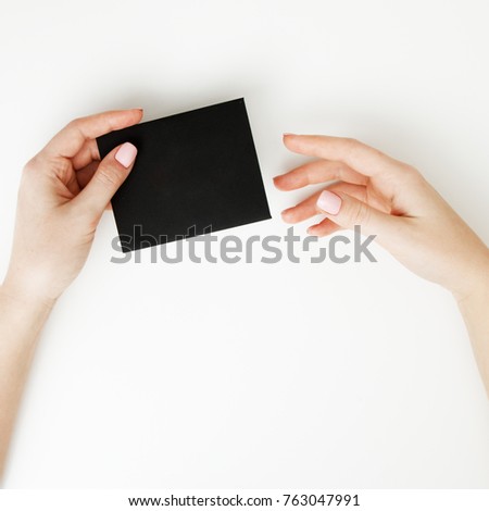 Flat lay, top view. Beauty and fashion concept. Beautiful female hands with red manicure. Minimal style. Minimalist photography. Composition with girl's hand holding discount card on white background