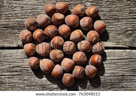 Several hazelnuts in shell on a wooden background, top view