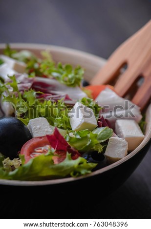 Greek salad and vegetables on the black wood table 