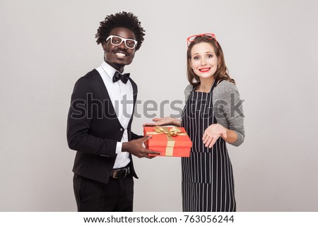 Businessman gives a gift for St. Valentine's Day her woman. Studio shot, gray background