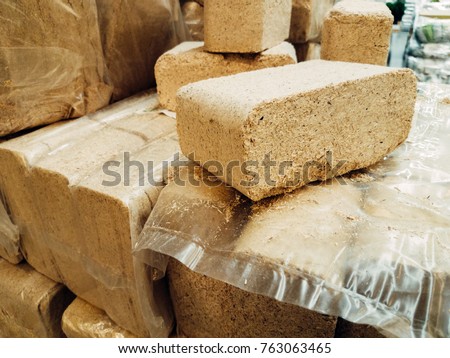Alternative fuel, eco fuel, bio fuel. Wood sawdust briquettes for stoves. Lean-burn with good heat output. Briquettes from sawdust on a green background. Royalty-Free Stock Photo #763063465