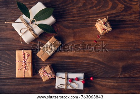 Christmas gifts decorated by festive decor on  brown rustic wooden table. Christmas and celebration concept. Toned with old style sepia colors. Top view.