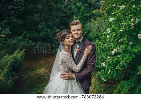 Groom kisses bride's cheek tender hugging her in the garden