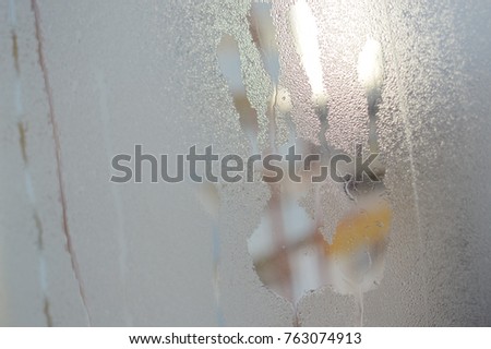 Closeup on hand palm print mark on window glass with condensation, rain or water drops and steam surface textured abstraction background