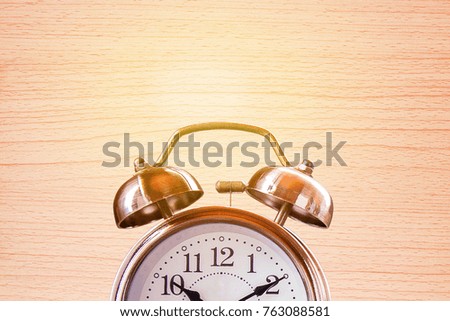 Close up retro alarm clock on a wooden table with blurred brick wall background. Photo in retro color image style. Top view with copy space for use.