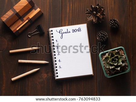Flat lay design of work desk with notebook on wooden background. New Year's composition with notebook. Space for text. New year resolution concepts. Planning of the new year