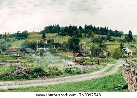 mountain landscape with a small cozy village on the flat land, a place in the autumn fog