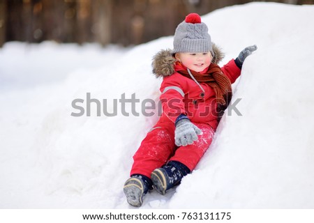 Little boy in red winter clothes having fun with fresh snow. Active outdoors leisure with children in winter. Kid during stroll in a snowy winter park