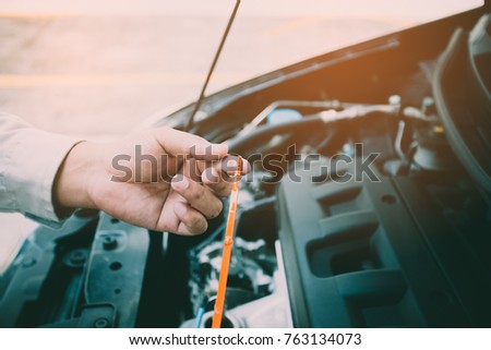 Car mechanic check oil level,Car repair service, Auto mechanic checking oil level in a engine.