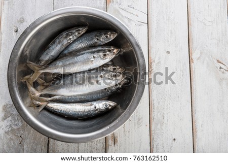 Fresh mackerel fish in metal bowl on wooden background
