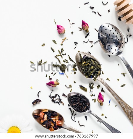 Variety of dried tea, dried herbal, green, black tea and fruit tea on vintage silverware tea spoons over white background with copy space negative space. Table top view
