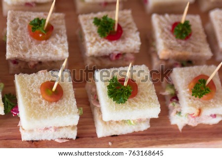 Canape  sandwiches with toothpicks and fresh vegetables on wooden board