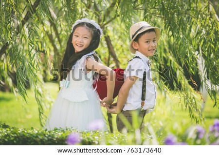 Little girl and boy holding red heart pillow  on white table in garden concept for valentine day , Valentine kids with heart pillow in garden.