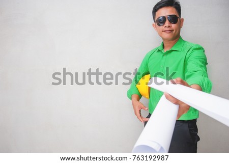 Thai young men civil engineer hand holding yellow hat and showing construction paper roll