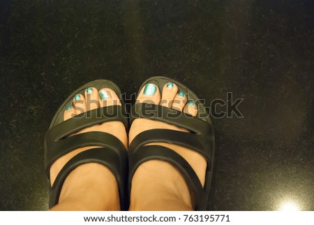 Natural lighting and shadow of blur woman's feet in dirty black slippers on  mall's floor in mall,Bangkok,Thailand.wooden background with copy space in holidays and chilling concept.