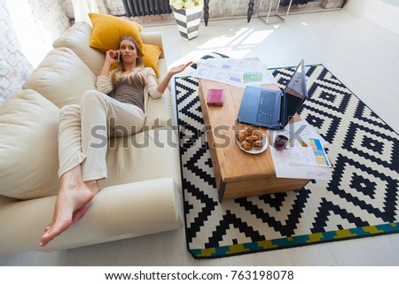 Top view on the young woman lying on the bed with laptop, phone and photo camera. Resting after the work. Business woman. freelancer.