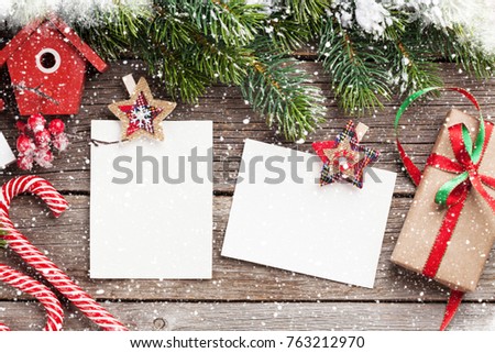 Christmas blank photo frames, birdhouse decor and snow fir tree on wooden table. Top view with space for your greetings