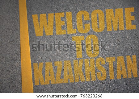asphalt road with text welcome to kazakhstan near yellow line. concept
