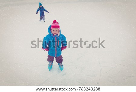 happy little girl and boy skating in winter
