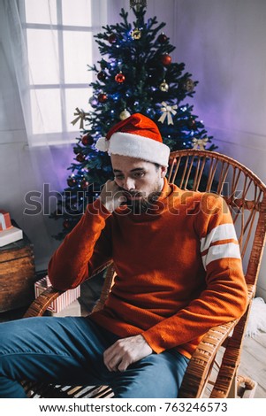 A vertical picture of sad and unhappy man sitting in the rocking chair in a bright room. He tired and bored because Christmas party was over last night and all of his friends has gona home. Now young