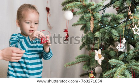 Cute blond preschool girl decorating christmas tree. Authentic family xmas time concept