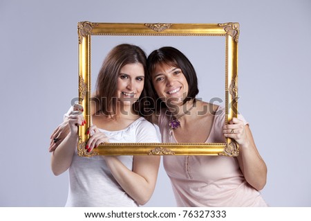 two beautiful woman inside an antique picture frame (isolated on gray)