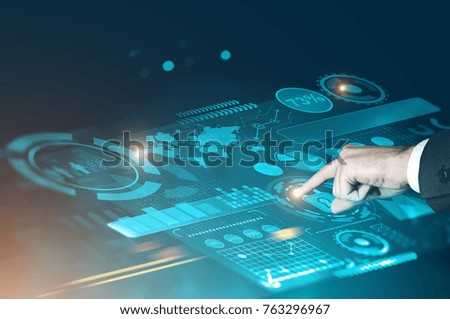 Businessman interacting with a futuristic HUD and graphs interface against a blurred blue background. Toned image double exposure mock up Elements of this image furnished by NASA