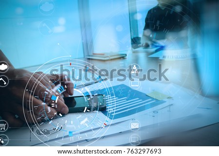 Hands of businessman using mobile phone in modern office with laptop and digital tablet computer with VR icon diagram