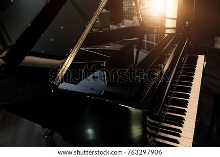 Black shiny grand piano with white keyboard in dark tone