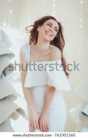 Beautiful young model smiling and posing at the photo studio, fashion fabric christmas tree on background.