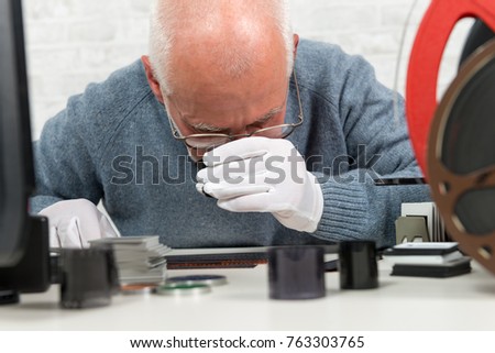 a man photographer looking at negative film with a magnifying glass