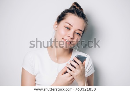 Happy young fit woman using cell phone while listening to music on smartphone