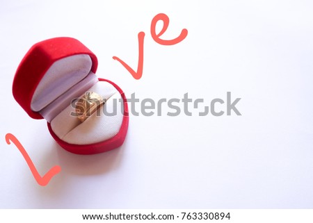 soft focus valentine day concept, golden ring in heart red box with love text on white background.