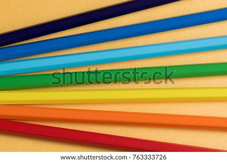 color pencils on orange  background. rainbow colors