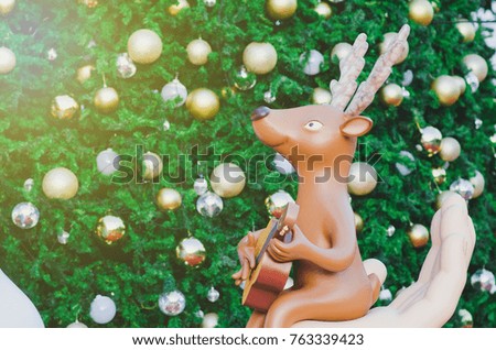 Reindeer model plays a guitar with a Christmas background.