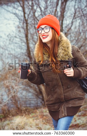 Cute funny smiling and laughing hipster girl wear coat eyeglasses in red hat and red lipstick at cold weather. Lifestyle modern young people, positive life and enjoying