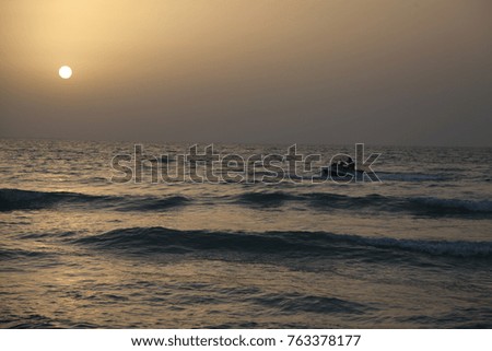 guy on a scooter on sea waves during sunset