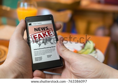 Man is holding smartphone and reading fake news on internet. Propaganda, disinformation and hoax concept. Royalty-Free Stock Photo #763386097