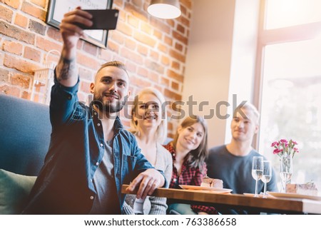 Group of people taking a selfie together in a restaurant. Modern days gadgets. Group picture.